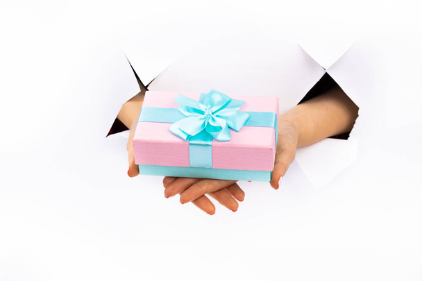 Pink gift with a blue ribbon in hands with manicure. Christmas. Paper Cut. - Foto, Imagen