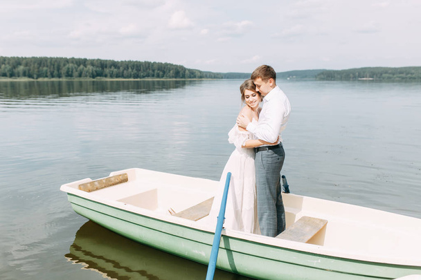  Stylish wedding in European style. Happy couple on a boat on the lake. - Zdjęcie, obraz