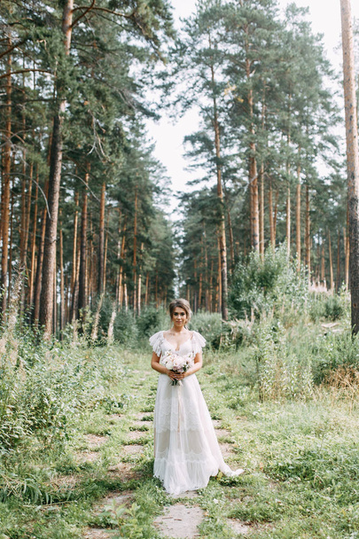 Elegant ceremony in European style. Beautiful bride in white flying dress in the forest.  - Fotó, kép