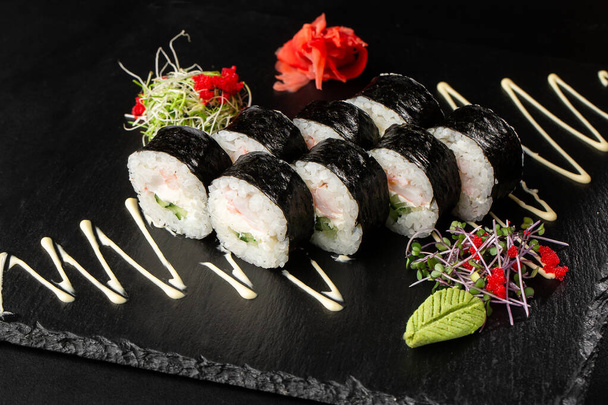 Sushi Rolls with shrimp, cucumber and Cream Cheese inside. Maki Futomaki Sushi Rolls with shrimp on black background. Sushi menu. Japanese food. Horizontal photo. - Foto, afbeelding