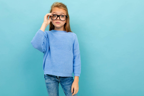 kicsi okos lány pózol szemüveg ellen kék háttér  - Fotó, kép