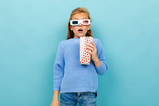 holčička pózuje s 3D brýle a popcorn proti modrému pozadí  - Fotografie, Obrázek