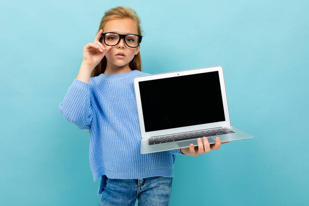 kislány pózol szemüveg és laptop ellen kék háttér  - Fotó, kép