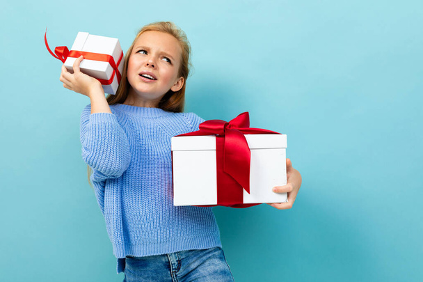 маленька дівчинка позує з двома подарунками на синьому фоні
  - Фото, зображення