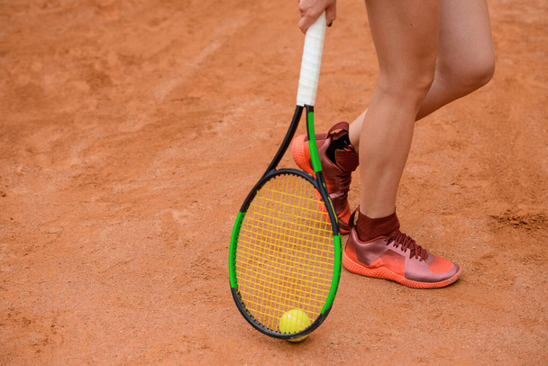 Woman holding a tennis racket near the ground, low section shot. - Foto, Imagem
