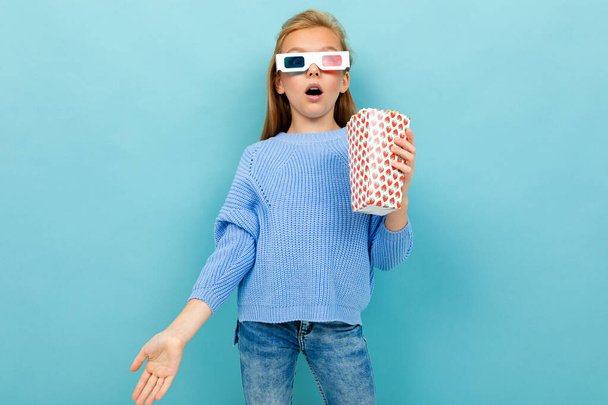 kislány pózol 3D-s szemüveg és popcorn ellen kék háttér  - Fotó, kép