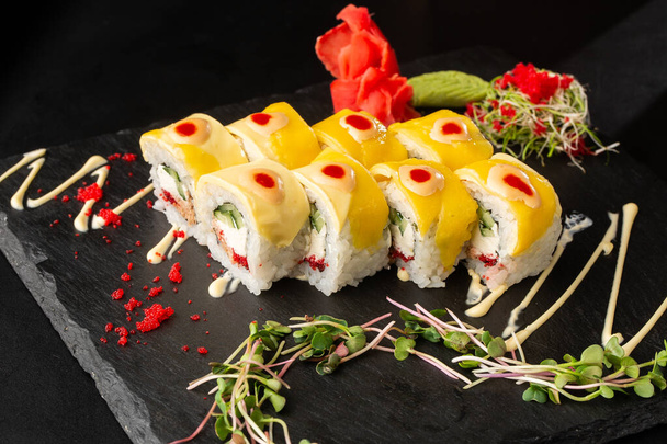 Sushi Rolls with cucumber, cheddar, flying fish caviar , tuna and Cream Cheese inside on black slate isolated. Philadelphia cheddar roll sushi with tuna. Sushi menu. Horizontal photo. - Foto, afbeelding