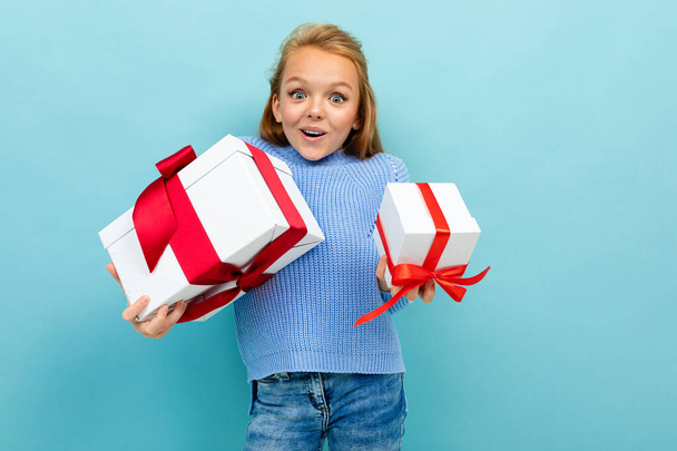 kislány pózol két ajándék ellen kék háttér  - Fotó, kép