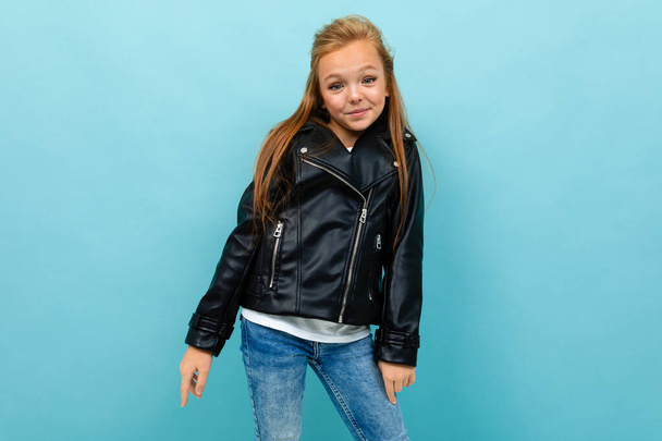piccola ragazza cool in giacca di pelle nera posa contro sfondo blu
  - Foto, immagini