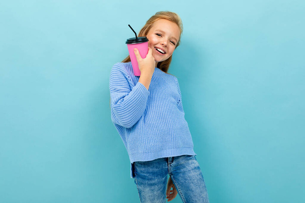 Nettes kleines Mädchen posiert mit Papierglas vor blauem Hintergrund  - Foto, Bild