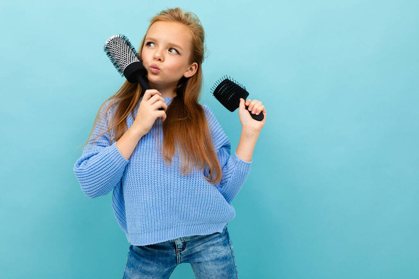 little girl posing with two hairbrushes against blue background  - Fotó, kép