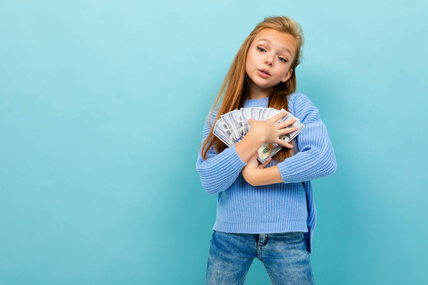 söpö pieni tyttö rahaa poseeraa sinistä taustaa vasten
  - Valokuva, kuva