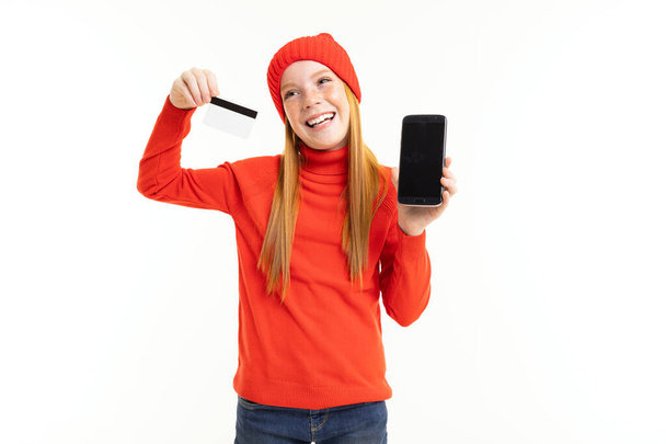 niña sosteniendo teléfono y tarjeta de crédito, concepto de compras en línea
  - Foto, imagen