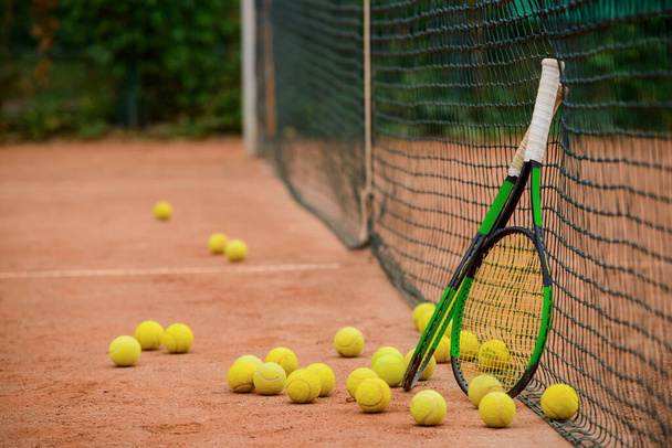 Tennis rackets and plenty of balls on the ground - Foto, afbeelding