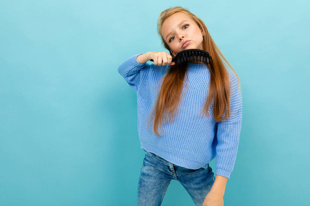little girl posing with hairbrush against blue background  - 写真・画像