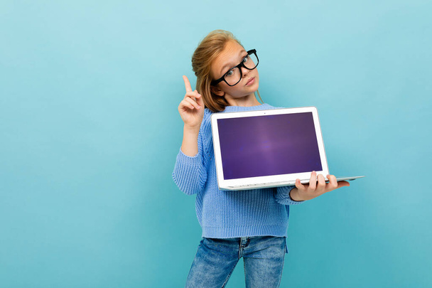 kleines Mädchen posiert mit Brille und Laptop vor blauem Hintergrund  - Foto, Bild