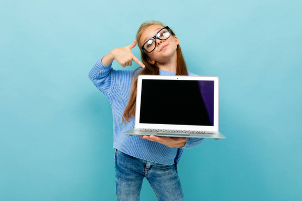 holčička pózuje s brýlemi a notebookem na modrém pozadí  - Fotografie, Obrázek