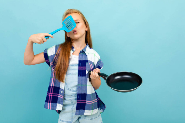 cute little girl posing with frying pan against blue background  - Фото, зображення