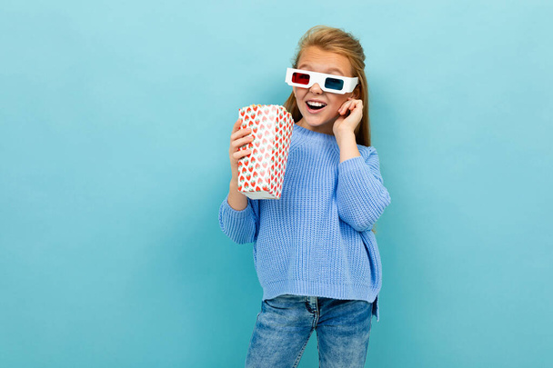 little girl posing with 3D glasses and popcorn against blue background  - Fotoğraf, Görsel