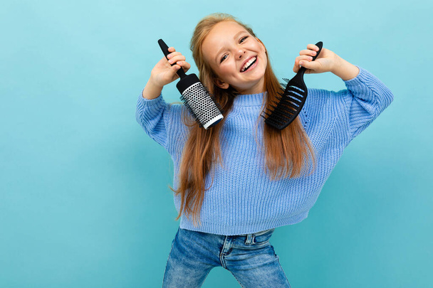 little girl posing with two hairbrushes against blue background  - Fotoğraf, Görsel