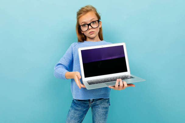 маленькая девочка позирует в очках и ноутбуке на синем фоне
  - Фото, изображение