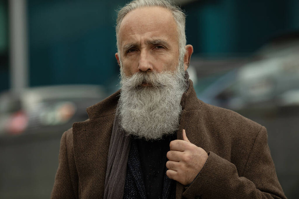 Portrait of handsome mature man, outdoors. Old man with a grey beard. Fashion look. - 写真・画像