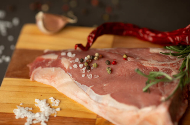 Steak raw. Barbecue Rib Eye Steak or rump steak on rustic table with rosemary. T-Bone steak. - Foto, afbeelding