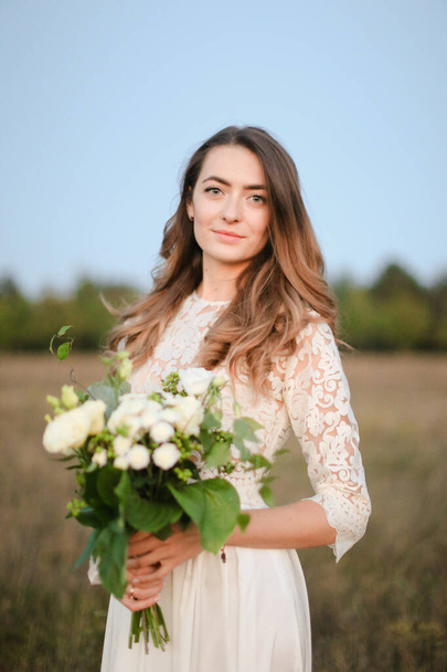Caucasienne belle mariée avec fond de bouquet blanc en arrière-plan steppe
. - Photo, image