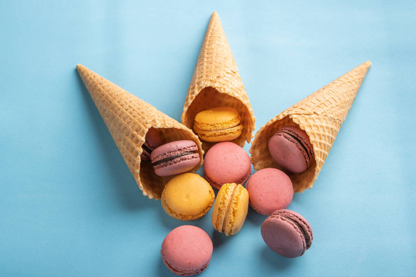 Macarons poured out of pastry cones on blue background. Top view - Fotografie, Obrázek