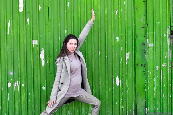 girl on a green background. In a warm gray coat. Portrait of the beautiful girl on a green background - Foto, Imagen