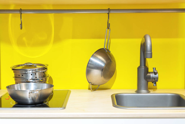 Kid's kitchen with washing, stove and utensils on a yellow background. - Photo, Image