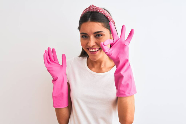 Young beautiful woman wearing clean gloves standing over isolated white background doing ok sign with fingers, excellent symbol - Photo, Image