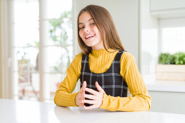 Genç, güzel sarışın kız evde sarı süveter giyiyor ellerini birleştirip gülümsüyor rahat ve neşeli. Başarı ve iyimser - Fotoğraf, Görsel