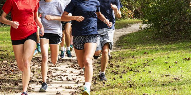 Group of runners running fast on a dirt path in a park - Photo, Image