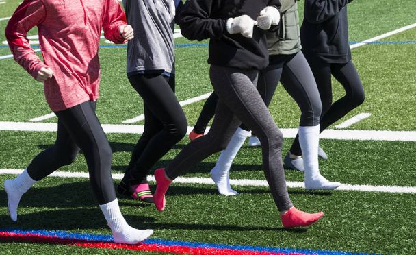 Girls running on green turf in socks on a cold day - Foto, Imagen