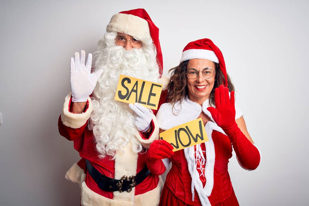 Pari yllään Santa puku tilalla wow ja myynti banneri yli eristetty valkoinen tausta luopuminen sanomalla hei onnellinen ja hymyilevä, ystävällinen tervetullut ele
 - Valokuva, kuva