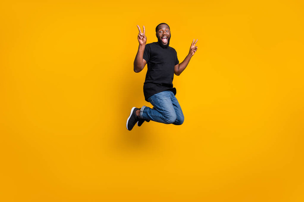 Full size photo of funky crazy afro american brunette hair guy jump fun spring weekends holidays make v-signs wear stylish outfit sneakers isolated over shine color background - Foto, Imagen