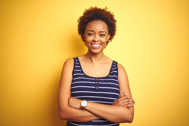 Beauitul donna afro-americana indossa una t-shirt estiva su sfondo giallo isolato volto felice sorridente con le braccia incrociate guardando la fotocamera. Persona positiva
. - Foto, immagini