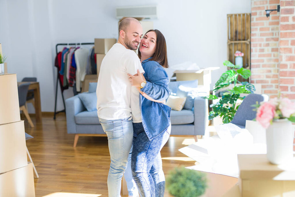 junges Paar tanzt im neuen Zuhause um Pappkartons herum, feiert - Foto, Bild