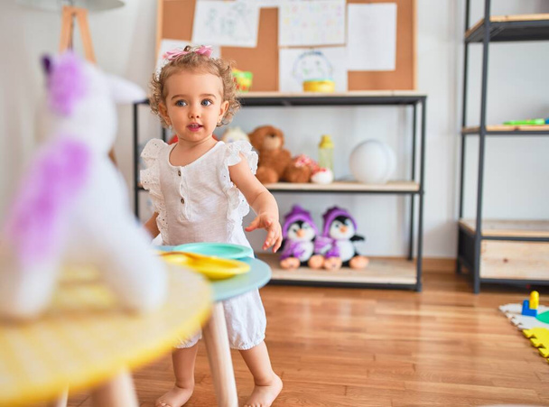Beautiful caucasian infant playing with toys at colorful playroom. Happy and playful at kindergarten. - Photo, Image
