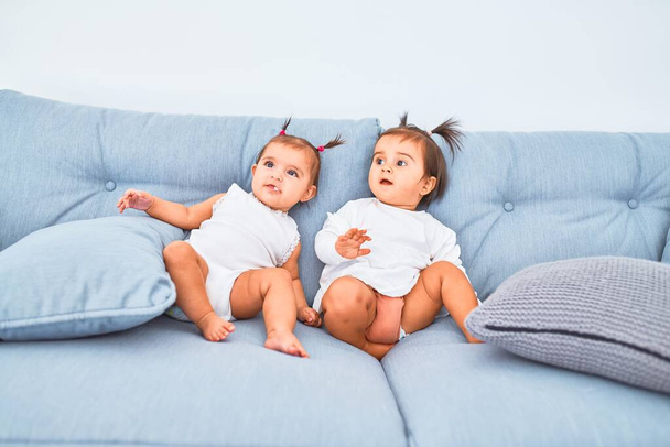 Kaunis pikkulapsi onnellisia tyttöjä leikkii yhdessä kotona päiväkoti istuu sohvalla
 - Valokuva, kuva