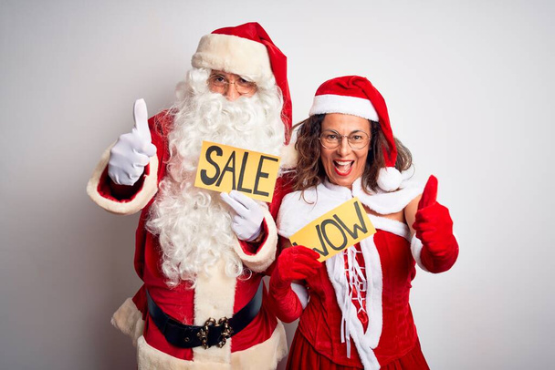 Pari yllään Santa puku tilalla wow ja myynti banneri yli eristetty valkoinen tausta hyväksymisestä tekee positiivinen ele käsin, peukalot ylös hymyillen ja onnellinen menestykseen. Voittajan ele
. - Valokuva, kuva