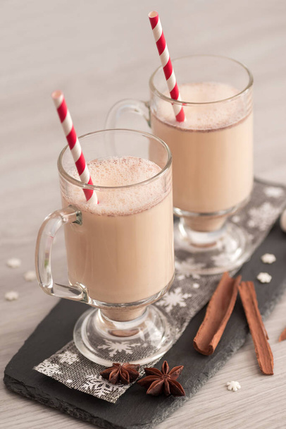 Eggnog in glass cups with a delicate foam, spices and a cinnamon stick - 写真・画像