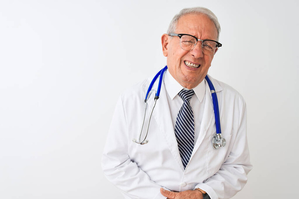 Senior grey-haired doctor man wearing stethoscope standing over isolated white background with hand on stomach because indigestion, painful illness feeling unwell. Ache concept. - 写真・画像