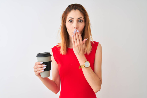 junge schöne rothaarige Frau trinkt Kaffee zum Mitnehmen über isolierten weißen Hintergrund Deckel Mund mit Hand schockiert vor Scham für Fehler, Ausdruck der Angst, Angst in der Stille, geheimes Konzept - Foto, Bild