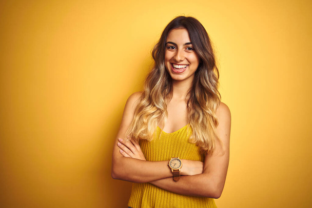 Молода красива жінка в футболці над жовтим ізольованим тлом щасливе обличчя, що посміхається схрещеними руками, дивлячись на камеру. Позитивна особа
. - Фото, зображення