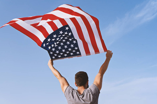 Homem por trás com as mãos levantadas e agitando Bandeira Americana
 - Foto, Imagem