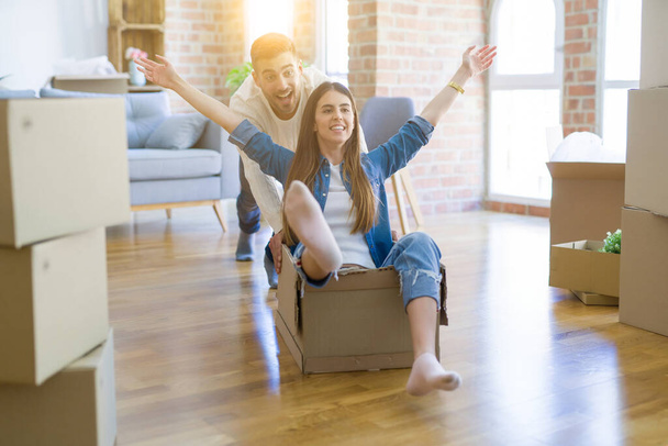 Young couple moving to a new home, having fun riding cardboard b - Photo, Image