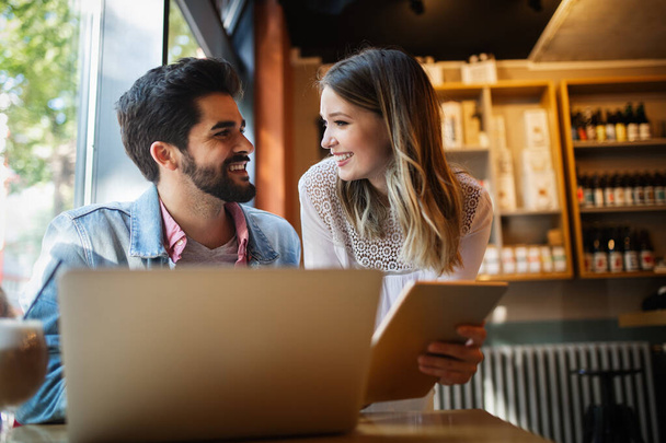 Jovem casal feliz está trabalhando no café no laptop e sorrindo
. - Foto, Imagem