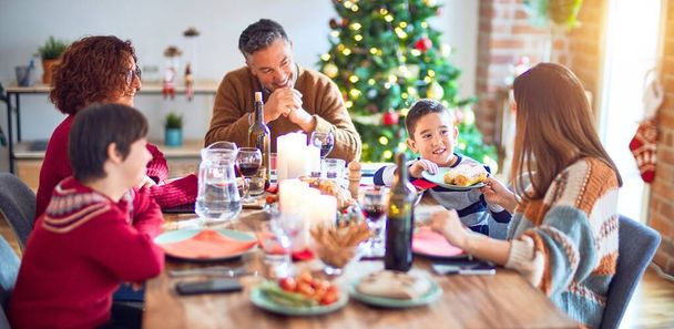 Beautiful family smiling happy and confident. Eating roasted turkey celebrating christmas at home - Foto, Imagem